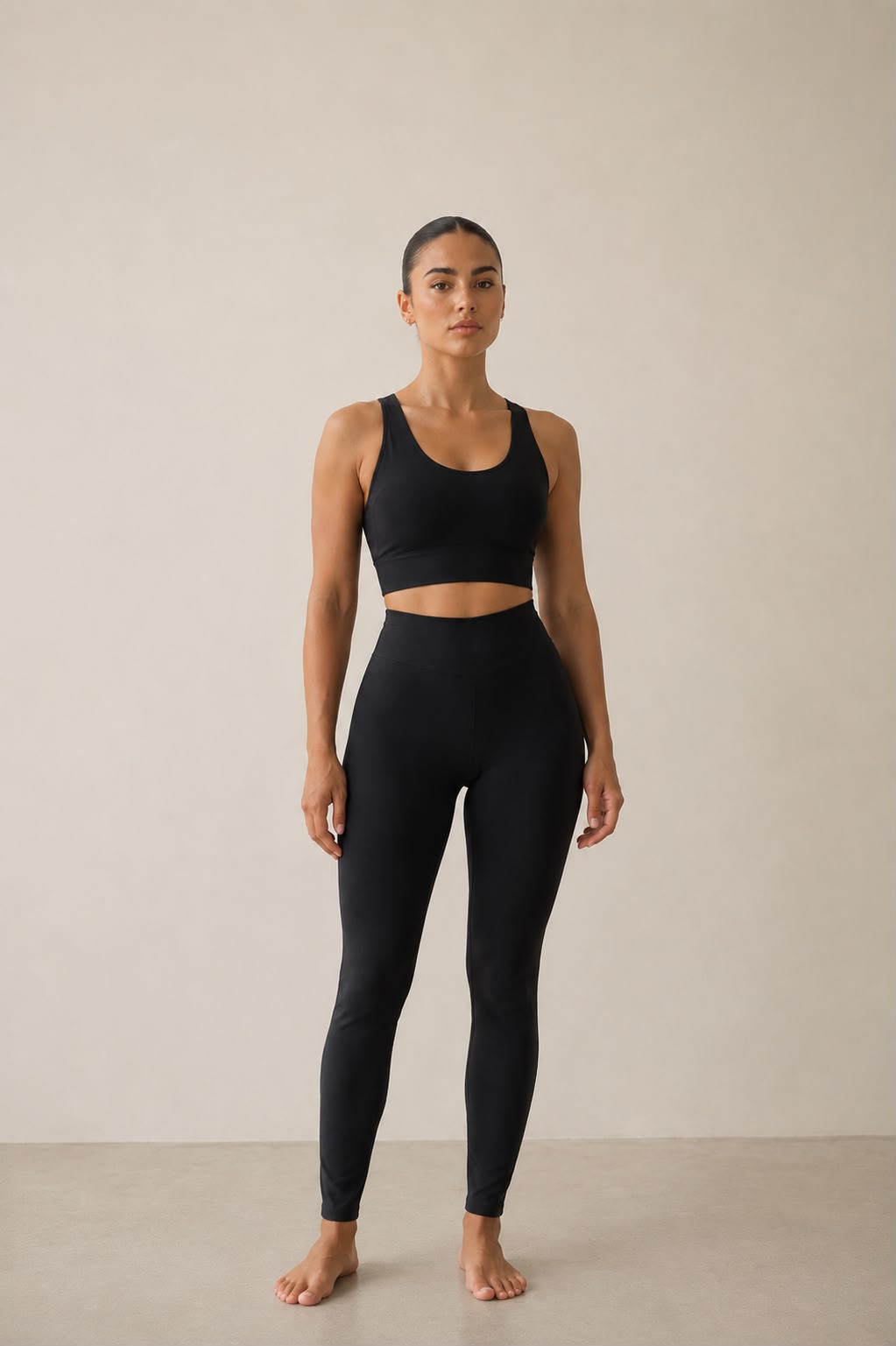 Femme portant l’ensemble activewear AURA Black GLIIMA, composé d’un legging taille haute noir et d’une brassière assortie, vue de face en studio minimaliste. Image