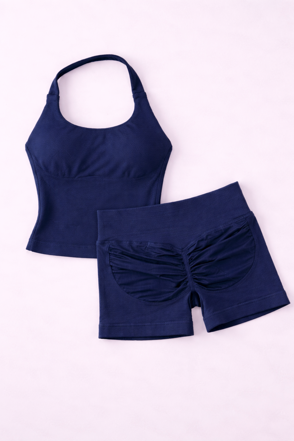 Ensemble activewear femme ALYA Navy GLIIMA présenté à plat, composé d’un haut ajusté col halter et d’un short taille haute avec léger scrunch au dos.