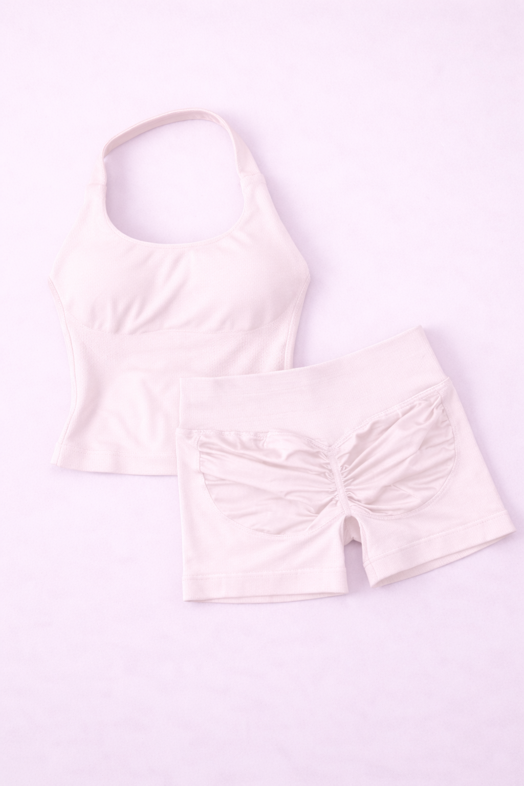 Ensemble activewear femme ALYA Pinky Cloud GLIIMA présenté à plat, composé d’un haut ajusté col halter et d’un short taille haute avec léger scrunch au dos.