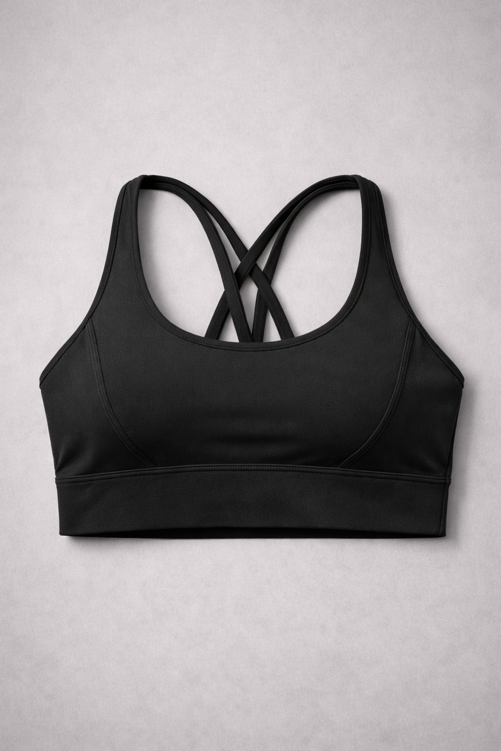 Brassière de sport AURA Black GLIIMA présentée à plat, avec fines bretelles croisées dans le dos.
