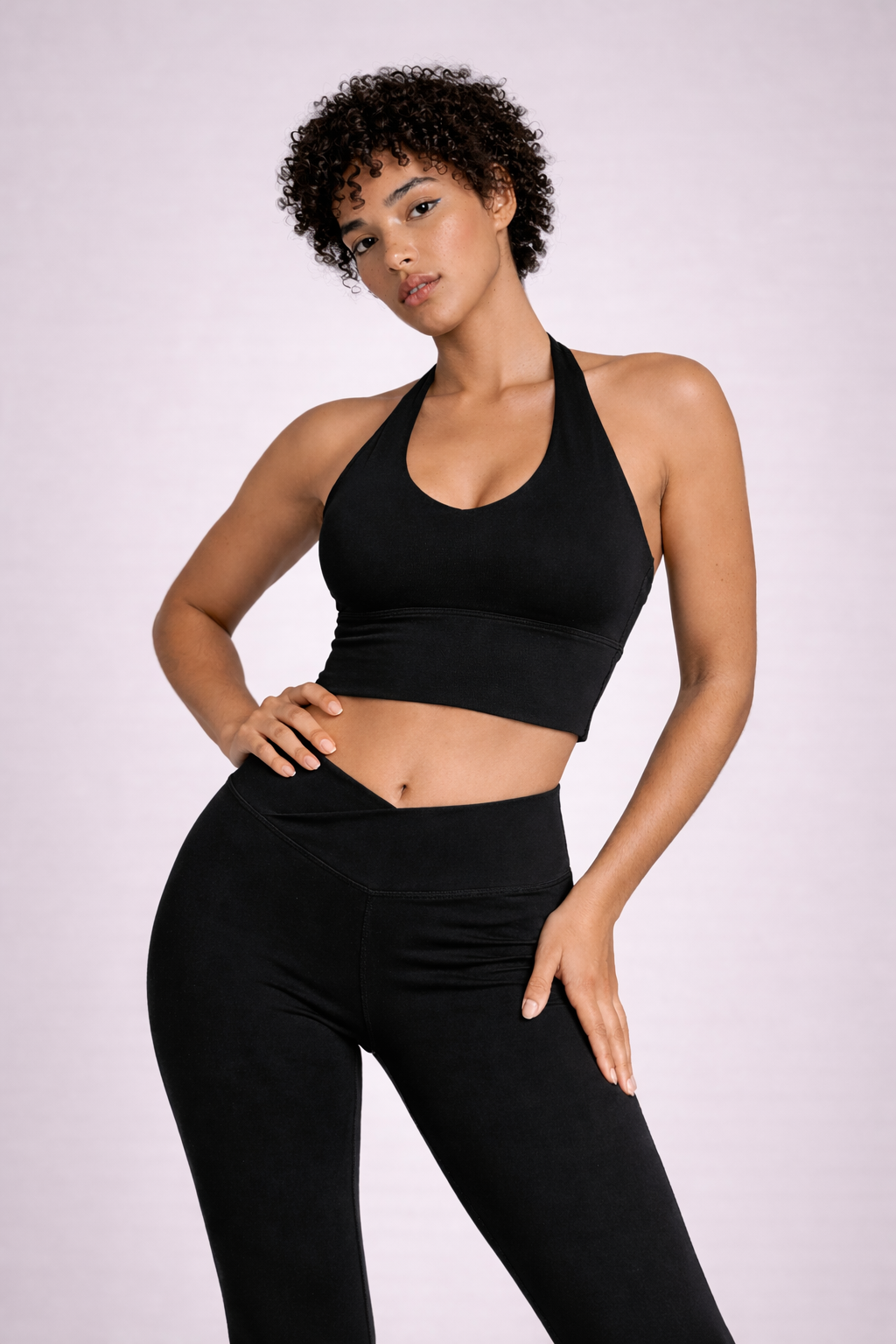 Vue de face rapprochée de l’ensemble LYRA black GLIIMA, avec brassière col halter et legging flare à taille haute croisée en V.