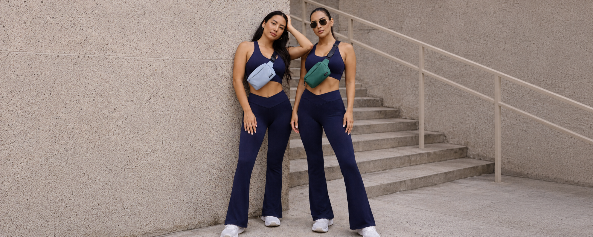 Deux femmes portant l’ensemble activewear LYRA Navy GLIIMA, avec legging flare taille haute et brassière col halter, dans un décor urbain.